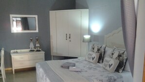 Un dormitorio con cama, cómoda, armario y espejo.