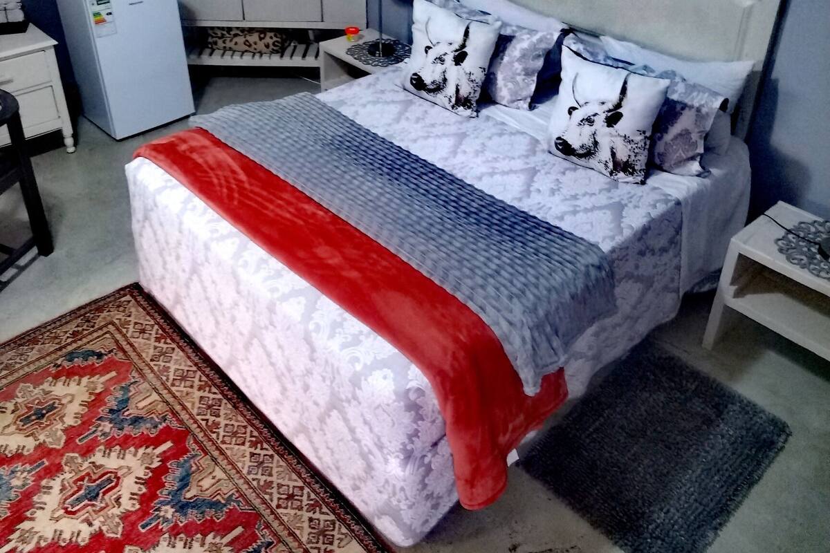 Une chambre à coucher comprenant un lit, une armoire, un bureau, une lampe et un réfrigérateur.