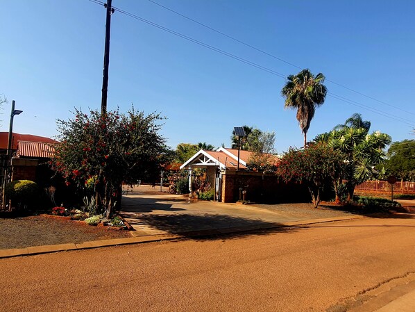 A residential street with houses, a covered driveway, and a palm tree.
