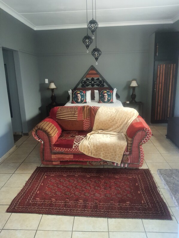 A room with a sofa, patterned rug, and decorative pillows. - Africa s Eden Guesthouse (Mookgopong)