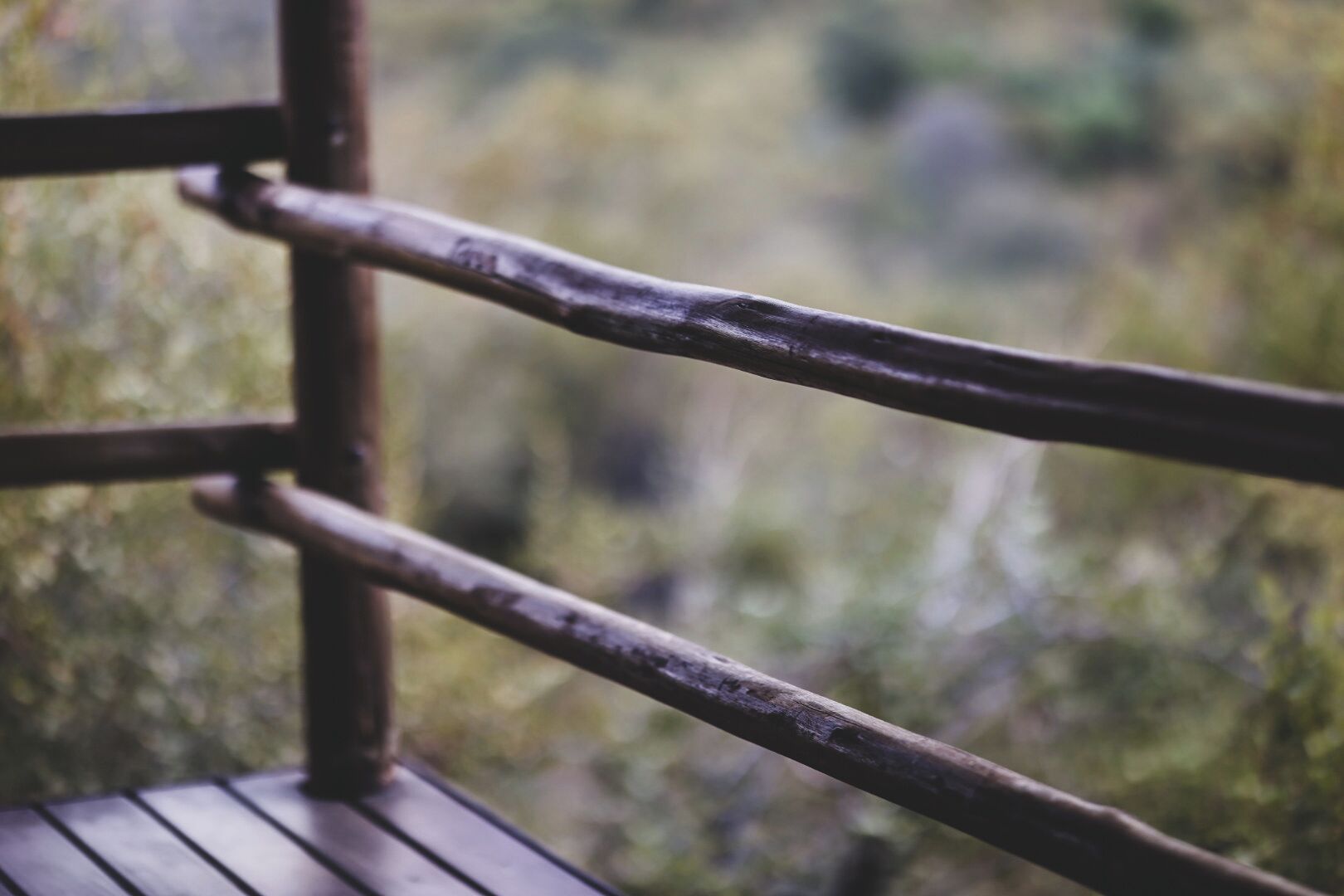 A wooden chair with a metal frame, positioned outdoors with a blurred natural background.