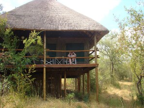 A thatched-roof structure with a balcony, surrounded by natural vegetation. - Muweti Bush Lodge (Phalaborwa)