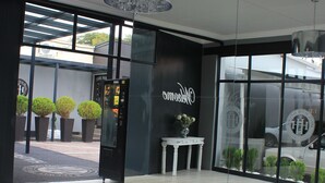 Eine moderne Hotellobby mit einer Rezeption, einem Automaten und einem großen Schaufenster mit Blick auf die Straße.