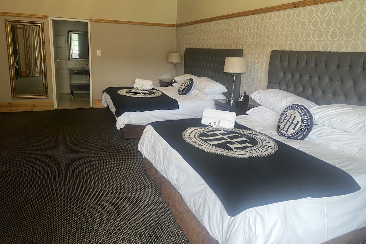 A hotel room with two beds, a bathroom, and a mirror.