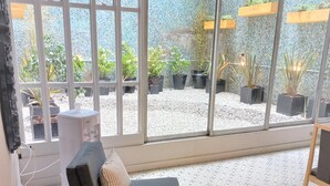 A modern room with a large window, a grey sofa, and a small table. - America Hotel (Mar del Plata)