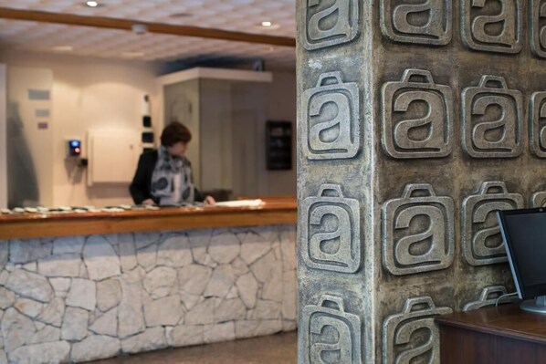 Zona de recepción con pared de piedra y mostrador de madera.