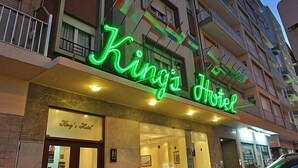 Exterior del Hotel King's, con un letrero de neón, una entrada visible y un balcón con barandillas.