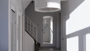 Una escalera con barandilla blanca, una lámpara moderna y una puerta al final.