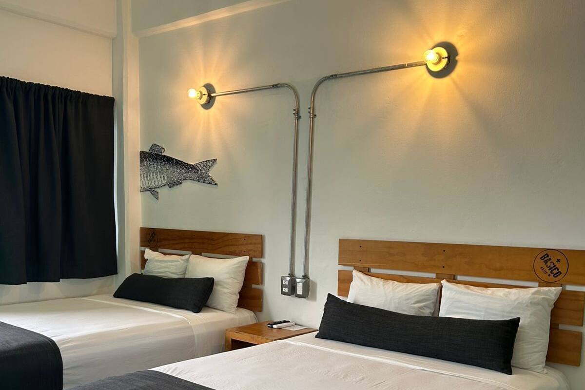 Habitación de hotel con dos camas, una mesita de noche, una lámpara de pared y un adorno de pez.