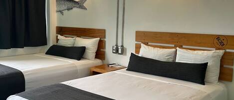 A hotel room with two beds, a nightstand, a wall-mounted lamp, and a fish decoration.