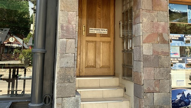 A stone building with a wooden door labeled 'Apart Chalten' and a sign above it. - Apart Chalten (El Calafate)