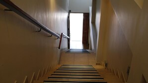 A staircase with a metal handrail and wooden steps leading to an open door at the top. - Apart Chalten (El Calafate)