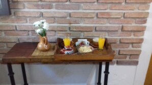 A breakfast table with a vase of flowers, a teapot, a cup, a bowl of cereal, and two glasses of orange juice.