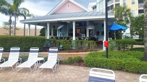 A beachside building with a covered patio, outdoor seating, and palm trees. - Lexington Vacations Kiss by Stark Hosp (Orlando)