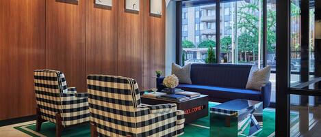 A modern lobby with wooden paneling, checkered armchairs, a blue sofa, and a coffee table.