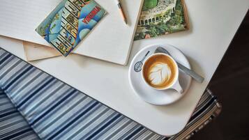 A notebook, a postcard, and a cup of coffee on a table.