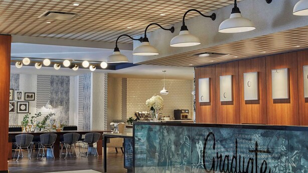 A reception area with a check-in counter labeled "Graduate Richmond," a tiled floor, and a ceiling with a grid pattern. - Graduate by Hilton Richmond (Richmond)