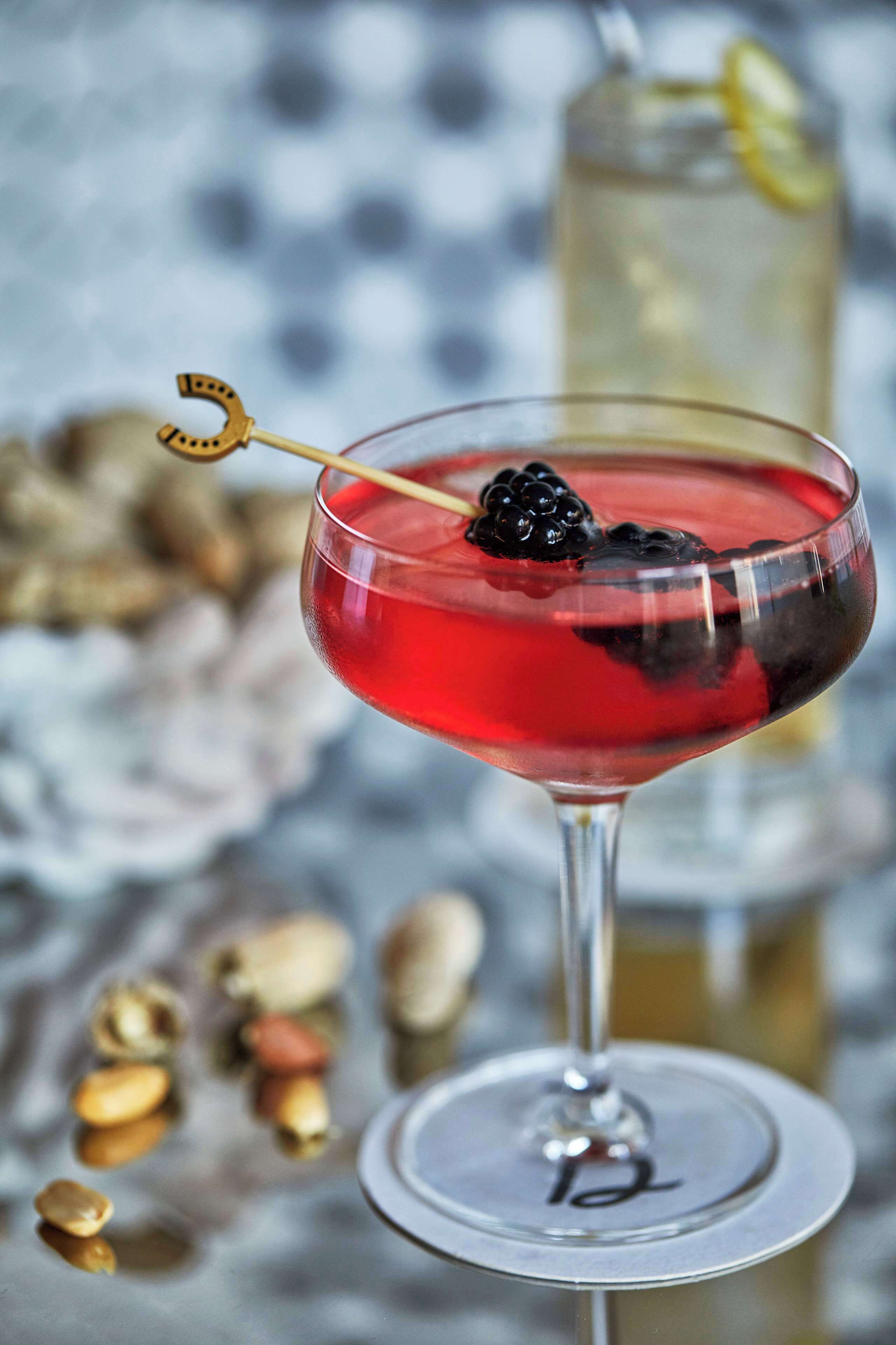 Un cocktail servi dans un verre à martini, garni d’une cerise et d’une tranche de citron.