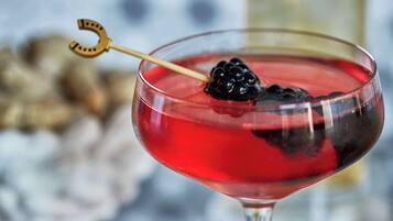 Un cocktail servi dans un verre à martini, garni d’une cerise et d’une tranche de citron.