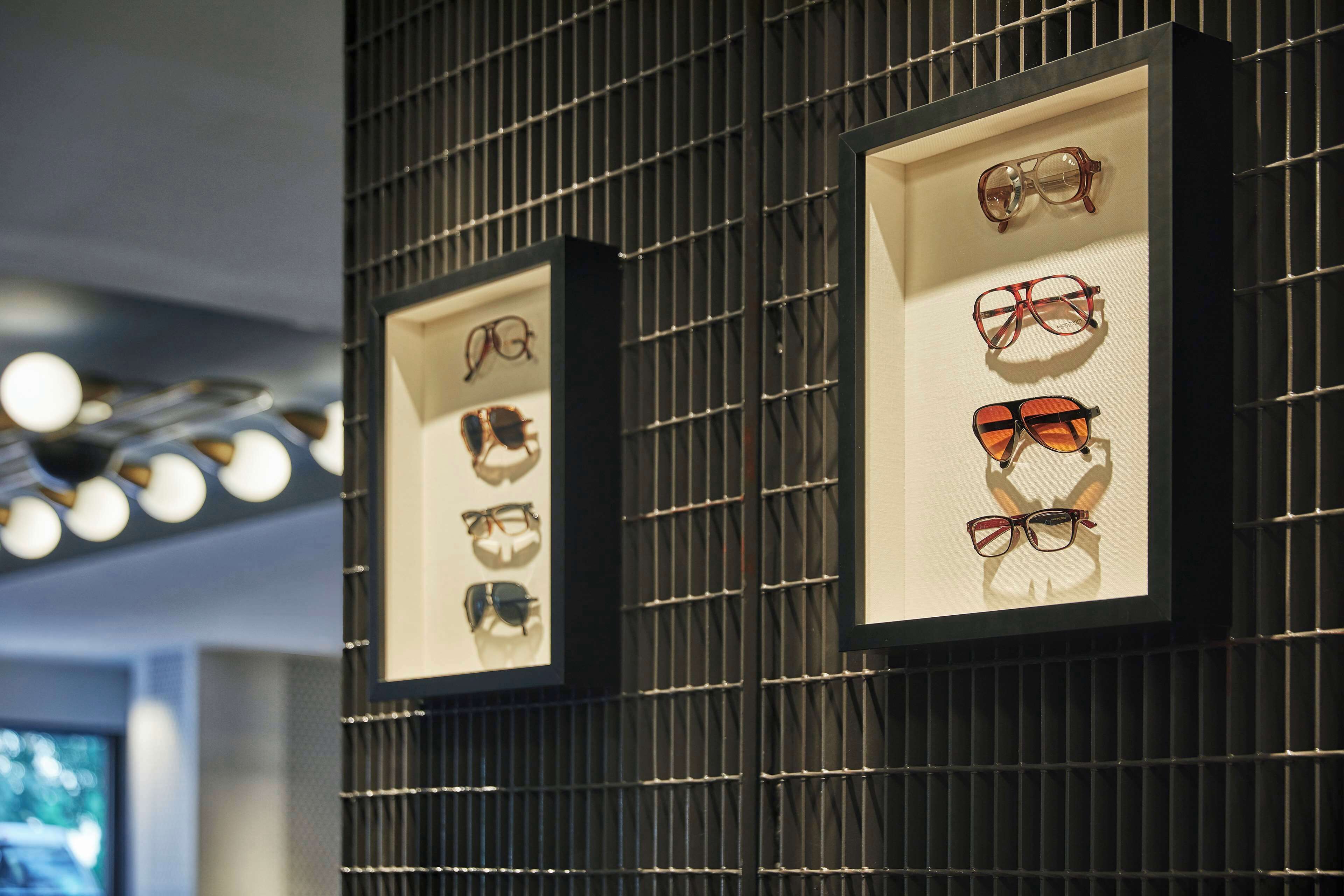 Framed eyewear displays on a wall with a grid pattern.