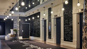 A modern lobby with a black and white patterned wall, a black and white patterned curtain, and a black and white patterned rug with the text "Welcome to our hotel". - Graduate by Hilton Richmond (Richmond)