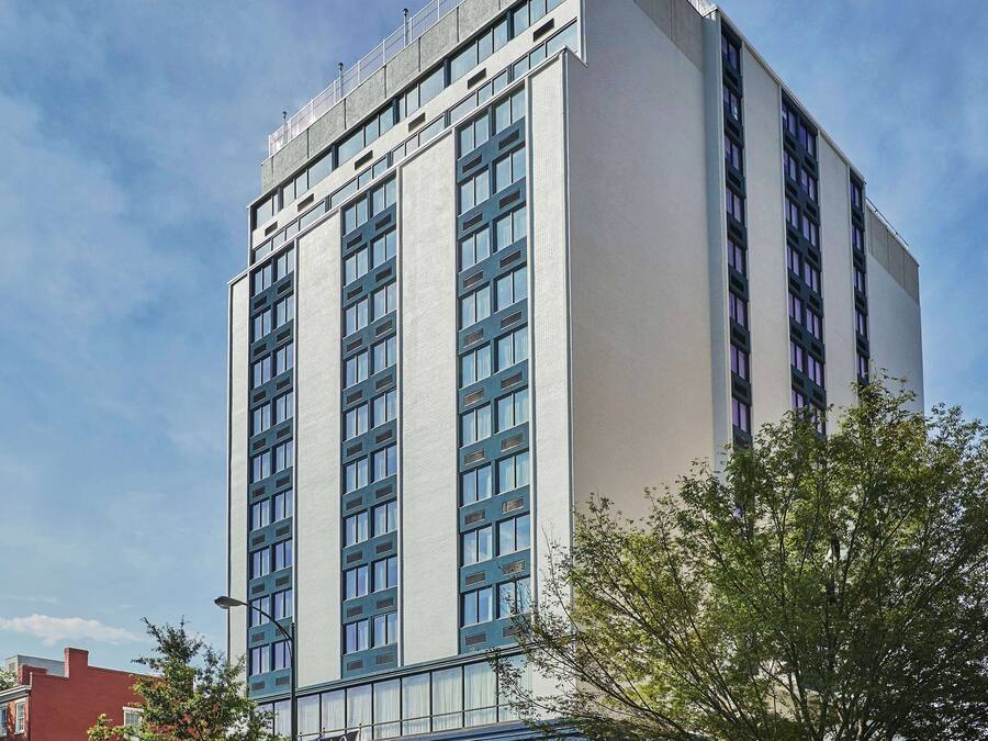 A high-rise hotel with a modern design, featuring a prominent entrance with a blue awning and a sign that reads "Graduate".