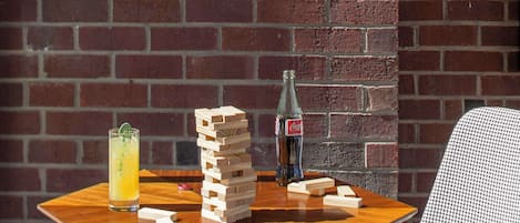 A wooden table with a stack of wooden blocks, a glass of orange juice, and a bottle of Coca-Cola. Two patterned chairs are positioned around the table.