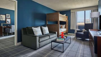 Ein Hotelzimmer mit Etagenbett, einer Schlafcouch, einem Schreibtisch und Blick auf die Stadt.