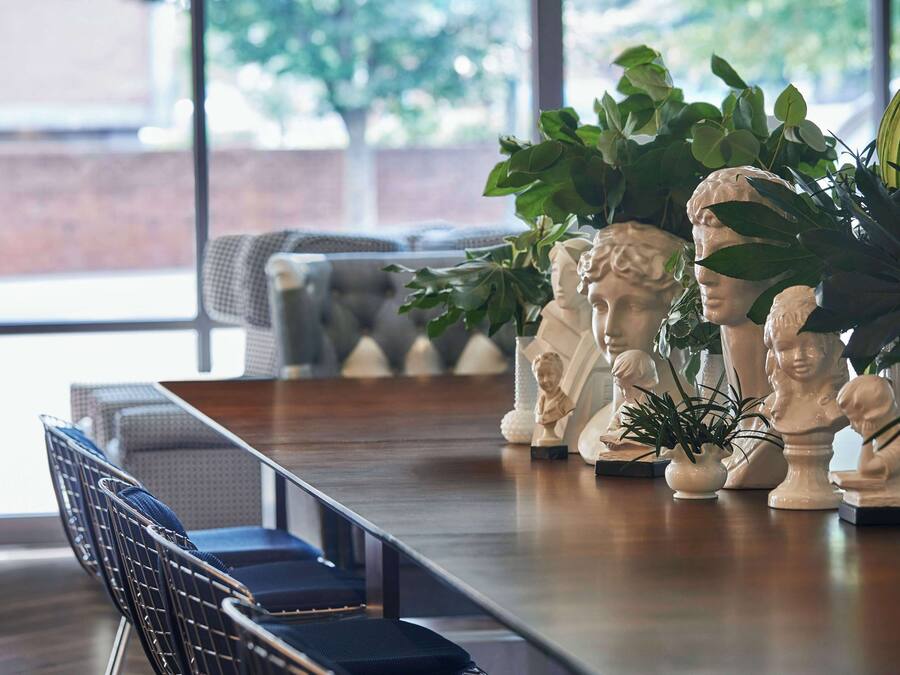 A dining area with a long wooden table, several chairs, and decorative busts.