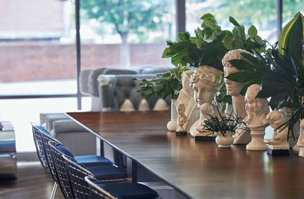 A dining area with a long wooden table, several chairs, and decorative busts.