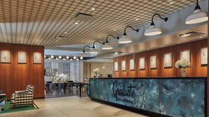 A reception area with a checkered chair, a reception desk with a 'Graduate Richmond' sign, and framed pictures on the wall. - Graduate by Hilton Richmond (Richmond)