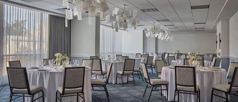 A conference room with multiple round tables, chairs, and hanging decorations.