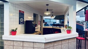 A modern bar area with a counter, seating, and a view of the outside. - Hotel Mediterraneo (Playas de Rosarito)