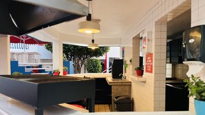 A modern kitchen with a black countertop, a sink, and a hanging light fixture. There are potted plants and a sign on the wall. - Hotel Mediterraneo (Playas de Rosarito)