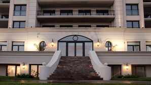 A multi-story hotel with a central entrance, outdoor lighting, and a well-maintained lawn. - Las Piedras Beach Experience I (Mar del Plata)