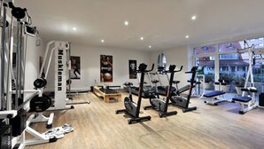 Un gimnasio con máquinas de cardio, equipo de levantamiento de pesas y un amplio ventanal con vista a la ciudad.