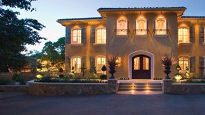 A large, two-story building with a symmetrical facade, multiple windows with shutters, and a central entrance with steps leading up to it. - Villa Arden Hills (Sacramento)