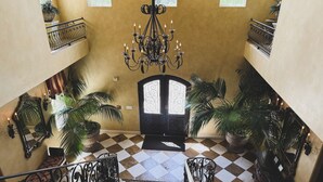 A grand staircase with a checkered floor, ornate black railings, and a chandelier. - Villa Arden Hills (Sacramento)
