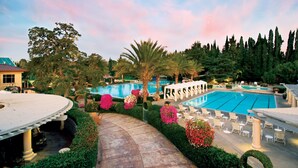 A resort pool area with multiple swimming pools, lounge chairs, and a covered seating area. - Villa Arden Hills (Sacramento)
