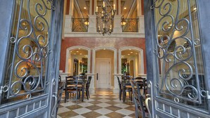 A grand entrance with ornate metal gates, a checkered floor, and a chandelier. - Villa Arden Hills (Sacramento)