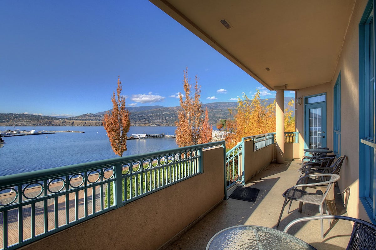 A balcony with a view of a lake, trees, and a distant mountain range.