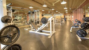 Un gimnasio con equipamiento para levantamiento de pesas, espejos y un interior limpio y bien iluminado.