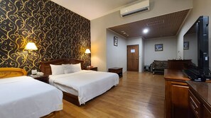A hotel room with two beds, a wooden desk, a television, and a patterned wallpaper. - Dibao motel (Ji'an)