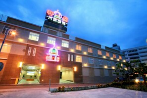 A hotel with a prominent neon sign, multiple windows, and a well-lit entrance. - Dibao motel (Ji'an)
