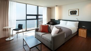 A modern hotel room with a large bed, a sofa, a small table, and a view of the sea. - Shilla Stay Busan Haeundae (Busan)