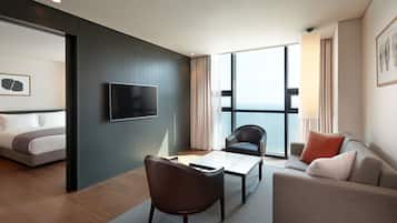 A modern hotel room with a bed, a TV, a sofa, and a dining table.