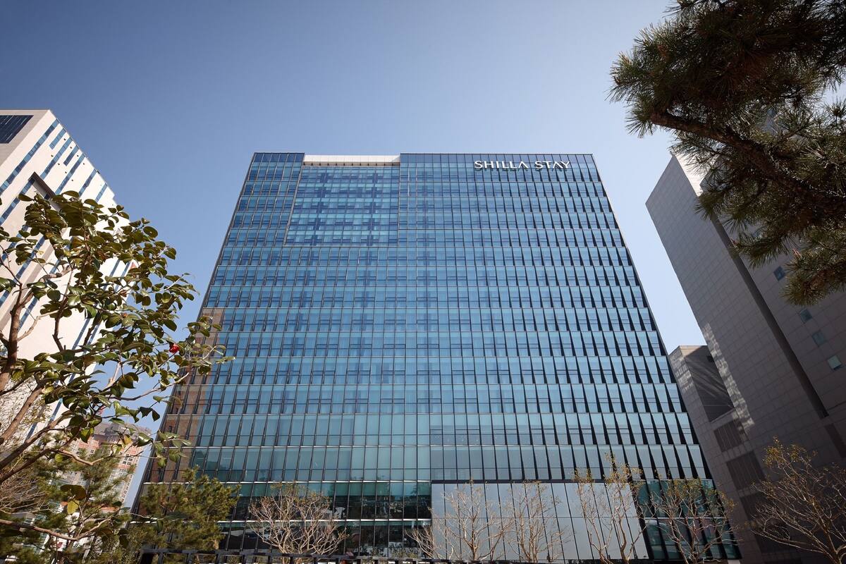 A modern glass skyscraper with the name "SHILLA STAY" on its facade.