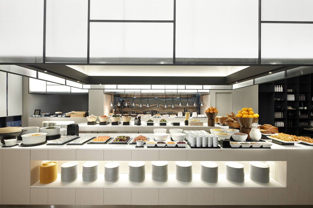 A modern buffet setup with various food items and dishes arranged on a long counter.