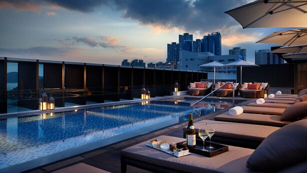A rooftop pool with lounge chairs, a bottle of wine, and a tray of cheese and crackers. - Shilla Stay Busan Haeundae (Busan)