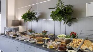A buffet setup with various food items and plants.